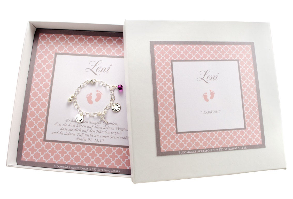 Gesamtansicht der personalisierten Geschenkbox mit rosa-weißgrauem Ornamentmuster, hier für den Namen "Leni" mit Geburtsdatum und Taufspruch.
Das Silberarmband wird innenliegend präsentiert.