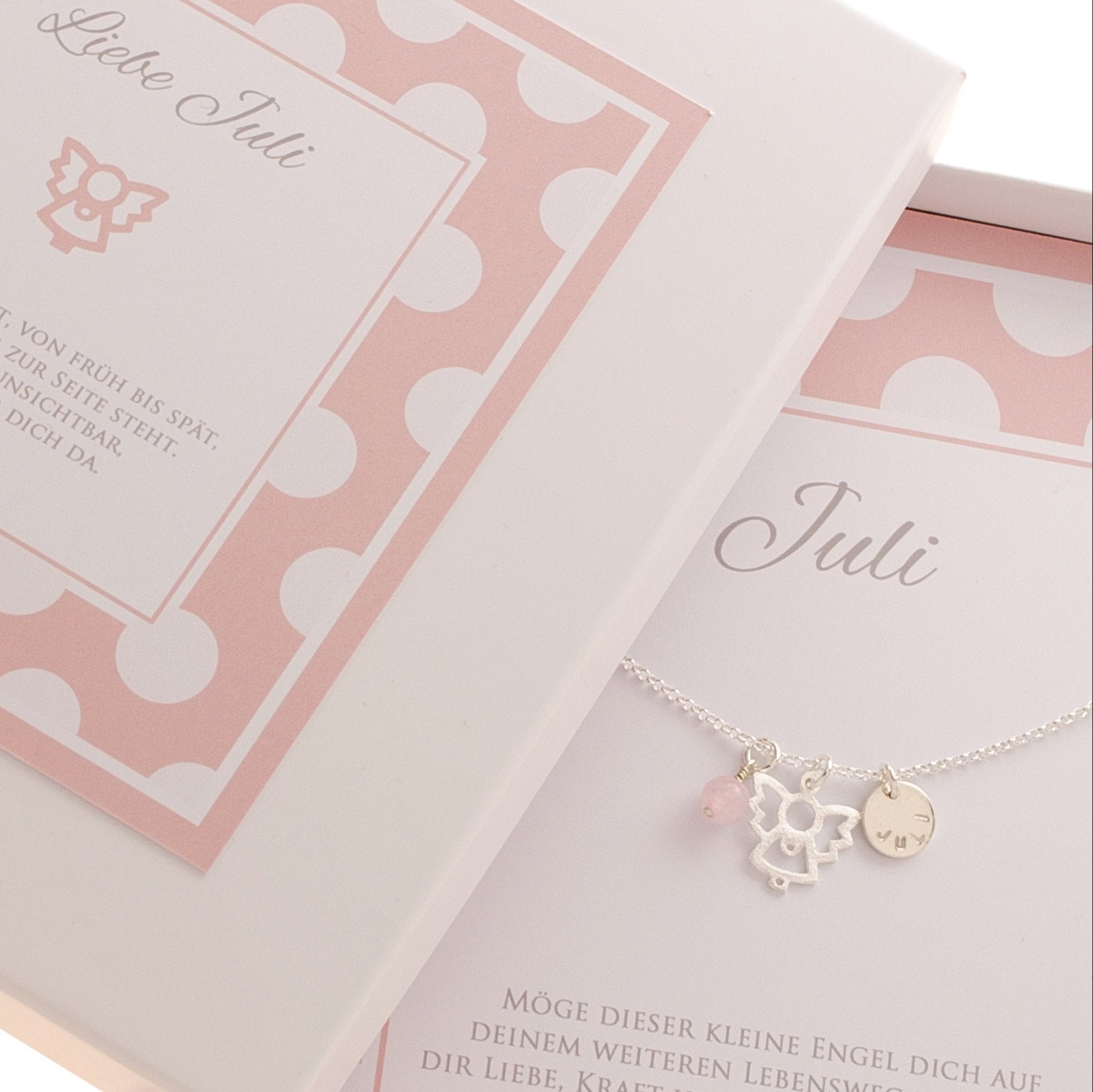 Offene Geschenkbox mit innenliegender  Silberkette mit Engel, Rosenquarz-Kugel und Namensanhänger. Oberhalb der Kette ist der Name in Schreibschrift gedruckt, unterhalb der Spruch 'Möge dieser keine Engel dich auf deinem weiteren Lebensweg begleiten, dir Liebe, Kraft und Zuversicht geben...'
