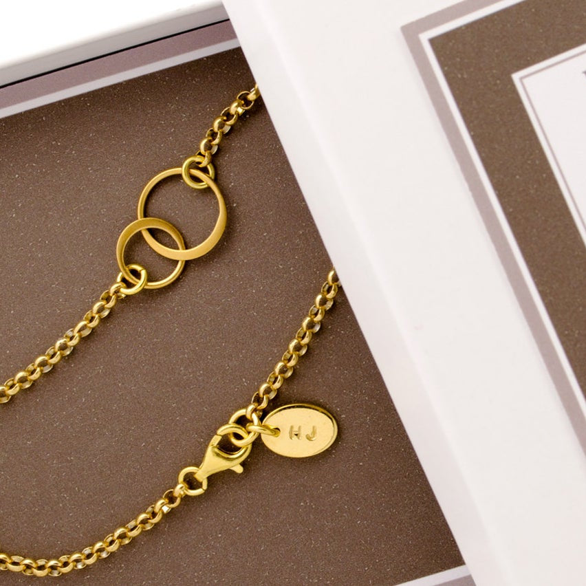 Freundschaftsarmband "Verschlungen" aus vergoldetem 925 Silber mit Initialen, präsentiert in einer braunen Geschenkbox mit dem englischen Freundschafts-Spruch: "Friendship is not one big thing, but one million little things."