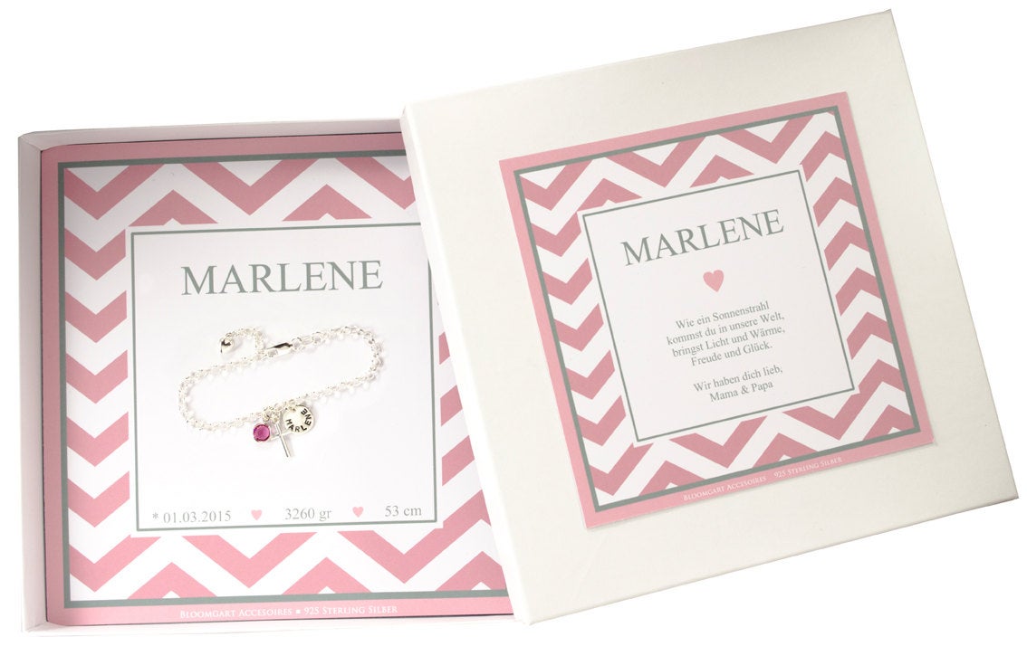 Gesamtansicht des Silberarmbandes mit rosa Oktober-Stein, Kreuz und Namensplättchen in einer personalisierten Geschenkbox mit rosa-weiß-grauem Zickzackmuster.