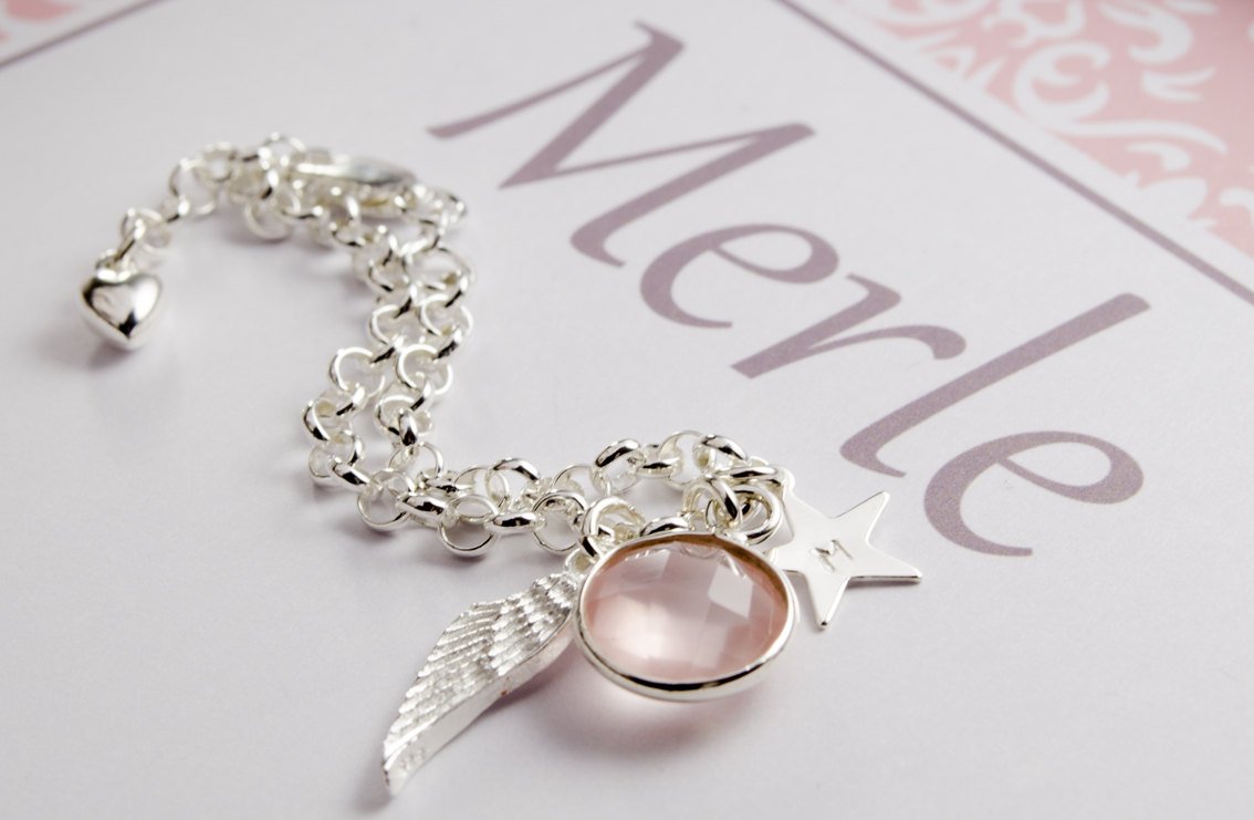 Ein süßes Geschenk zur Babytaufe, fier für 'Merle' personalisiert. Das Armband liegt in Wellen unter dem Namenszug 'Merle'.