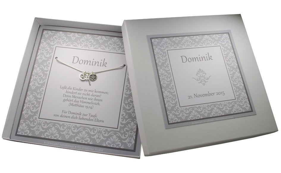 Gesamtansicht der edel Geschenkbox mit grau-weißem Ornamentmuster, personalisiert für Dominik zur Taufe. Innenliegend ist die 925 Sterlingsilber Kette mit den Anhängern Taufring, Engel, Kreuz und Namensgravur-Taler befestigt.