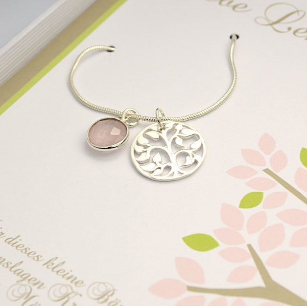 Detailansicht einer Schlangenkette mit rundem stilisierten Lebensbaum aus 925 Silber und  Rosenquarz-Anhänger präsentiert in einer rosa-hellgrün-weißen Geschenkbox.