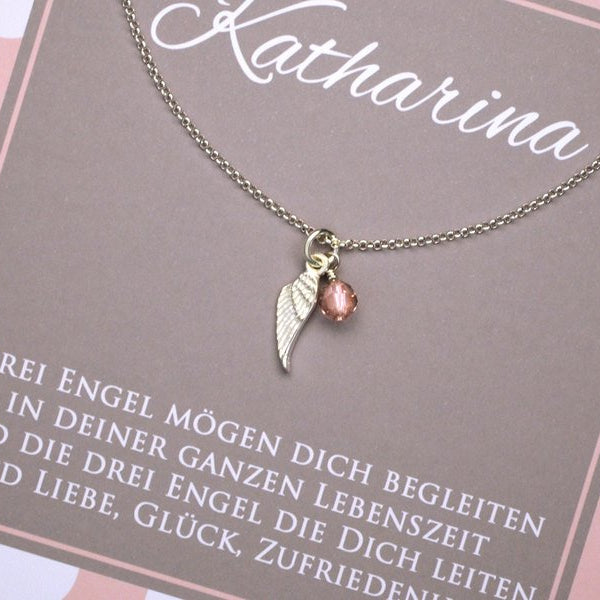 Detailansicht einer Silberkette mit Engelsflügel aus 925 Sterling Silber und rosa Glücksstein als Taufgeschenk fürs Patenkind, verpackt in einer personalisierten rosa-weiß gepunkteten Geschenkbox.