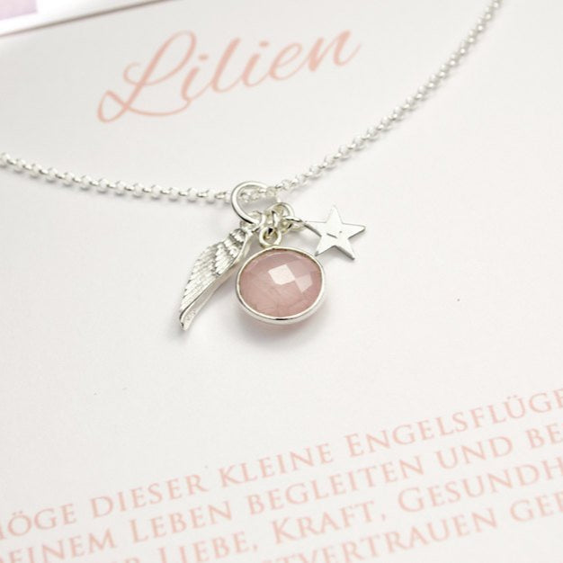 Detailansicht einer Silberkette mit Dreieranhänger, bestehend aus einem Engelsflügel, einem Rosenquarz und einem Stern mit Initial.