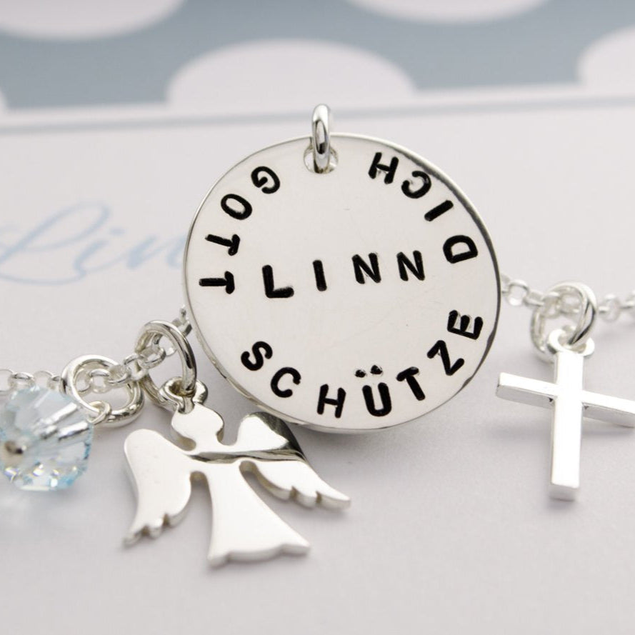 Detailansicht der Schutzengelkette mit Gravurtaler, hier mit 'Gott schütze dich" und Namen 'Linn' von Hand gestempelt.