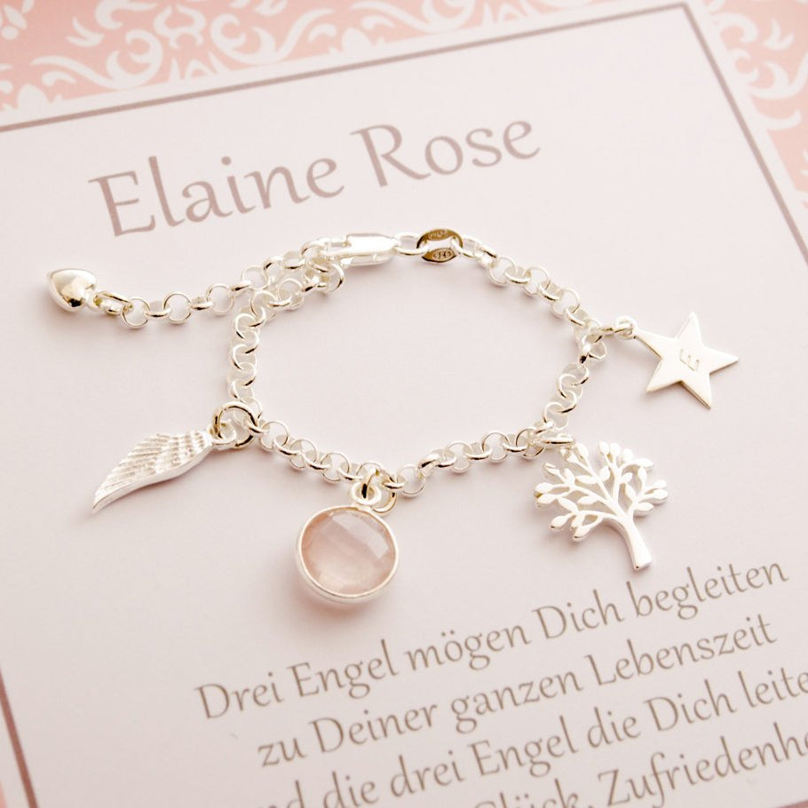 Makroaufnahme des Silberarmbandes zur Taufe von 'Elaine Rose' mit personalisiertem Geschenkkarton in rosa-weiß-grau Tönen und persönlichem Taufspruch 'Drei Engel mögen dich begleiten zu deiner ganzen Lebenszeit...'