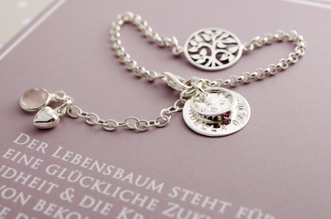 Detailansicht eines personalisierten Sterling Silber Taufarmbandes mit Lebensbaum, Engel, Namenstaler und Taufring.