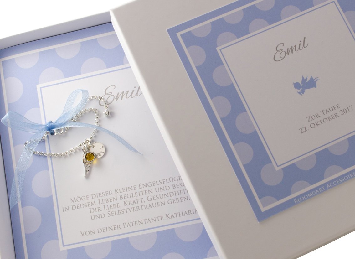Blau-weiß gepunktete Geschenkbox personalisiert für das Patenkind 'Emil' von der Patentante Katharina. Innenliegend ist das Gliederarmband mit Flügel, Geburtsstein und Namensplättchen an einem zarten Schleifenband befestigt.