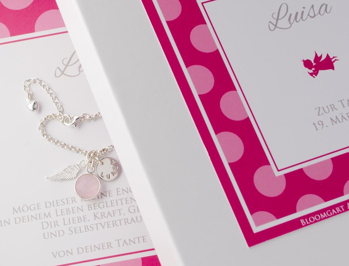 Silberarmband mit Engelsflügel, Namensgravur und Rosenquarz in einer personalisierten Geschenkbox mit rosa-rotem Punkte-Muster. Das Namensarmband ist aus 925 Sterling Silber von Hand angefertigt.
