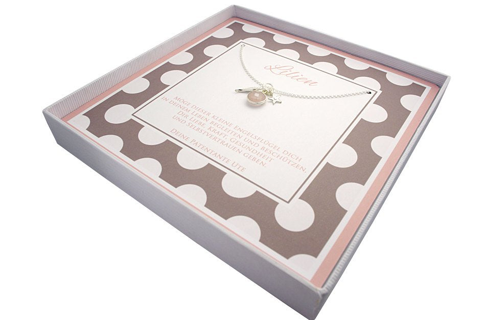 Innenansicht einer beige-weiß-rosa farbigen Geschenkbox. Innenliegend befindet sich eine 925 Silberkette mit Dreieranhänger, bestehend aus einem Engelsflügel, einem Rosenquarz und einem Stern mit Initial.