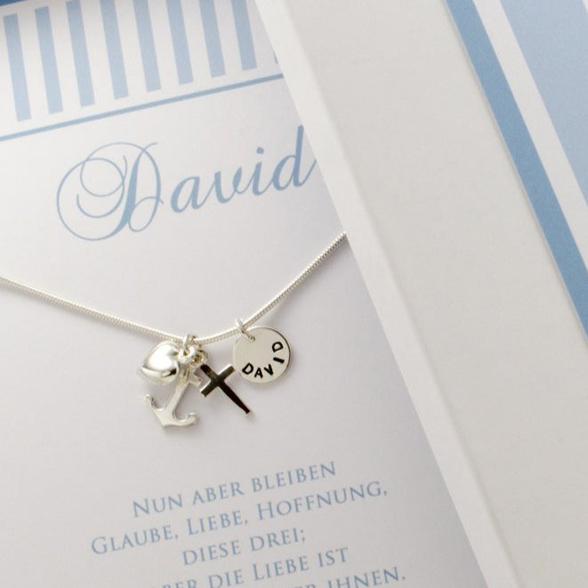Detailansicht einer Taufkette für Jungen mit Glaube-Liebe-Hoffnung Anhängern. Die Silberkette wird präsentiert in einer hellblauen, personalisierten Bloomgart Geschenkbox.