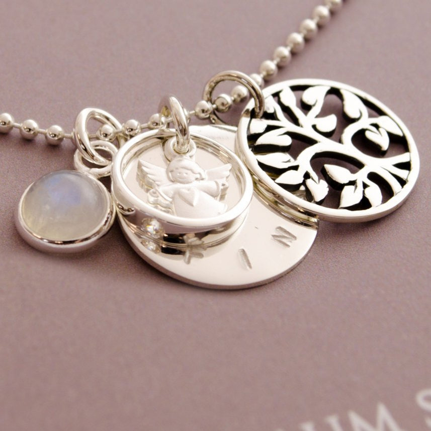 Zauberhafte Detailansicht einer 925 Silber Taufkette mit Lebensbaum, Engel im Taufring, Mondstein und Namenanhänger.