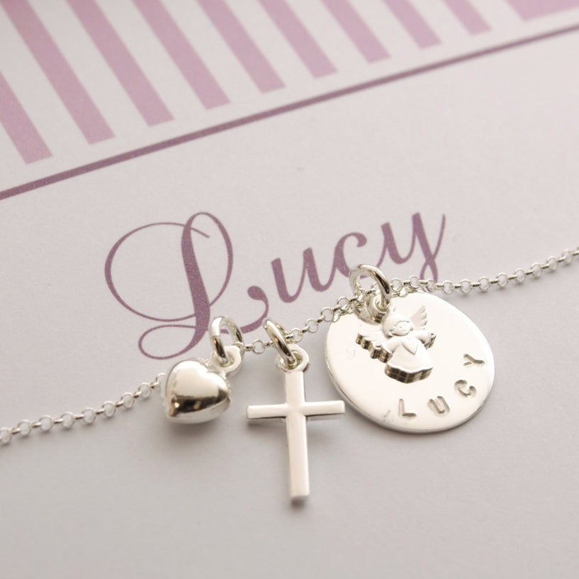 Detailansicht einer filigranen Namenskette mit Schutzengel, Kreuz und Herz-Anhänger, personalisiert für 'Lucy'.